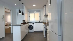 Une cuisine moderne avec des meubles blancs, un lave-linge et un réfrigérateur.