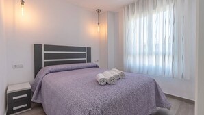Une chambre à coucher moderne avec un lit, une table de chevet et des rideaux.