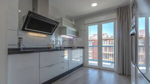 Une cuisine moderne avec des armoires blanches, un comptoir noir et un téléviseur encastré.