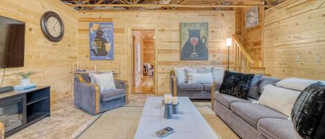A cozy log cabin interior with a living room featuring a sofa, a coffee table, and a TV stand.