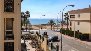 Un quartier résidentiel situé sur la côte, avec une rue menant à la plage, des palmiers et une vue dégagée sur la mer.