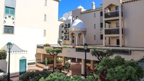 Une cour intérieure avec une fontaine centrale, entourée de bâtiments à l’architecture traditionnelle, notamment des structures à coupole et des balcons.