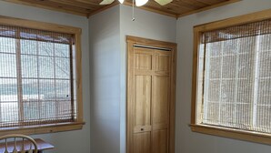 A bedroom with a bed, a chair, a desk, and a wooden door. - Lakefront All Season Home (Sabattus)