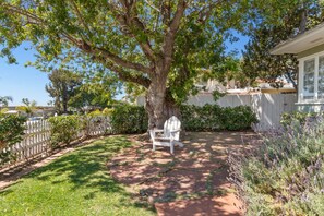 Relax in the serene backyard, surrounded by lush greenery and a tranquil atmosphere.
