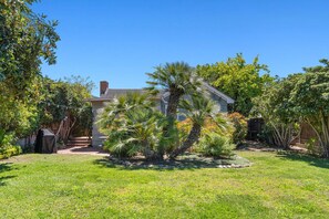 Enjoy a tranquil outdoor space with a well-maintained lawn and variety of plants, including palm trees, and a barbecue grill for outdoor cooking.