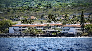 A coastal hotel with multiple buildings, a beachfront, and lush greenery in the background.