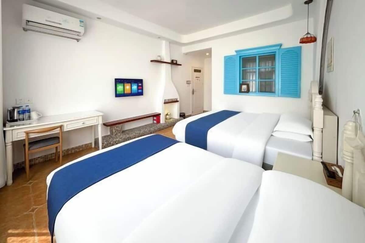 A hotel room with two beds, a desk, and a TV.