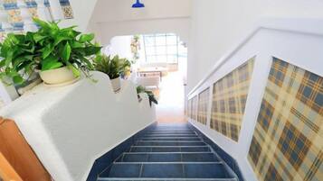A staircase with a white wall and a blue-tiled floor, leading to an upper level.