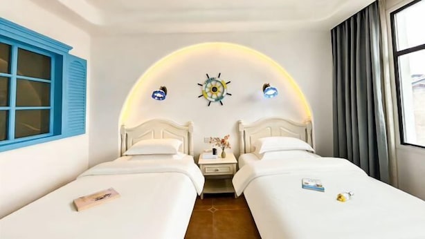A hotel room with two beds, a small table with a vase, and a wall clock. - No. 1 Inn @ the Corner (Zhangjiajie)
