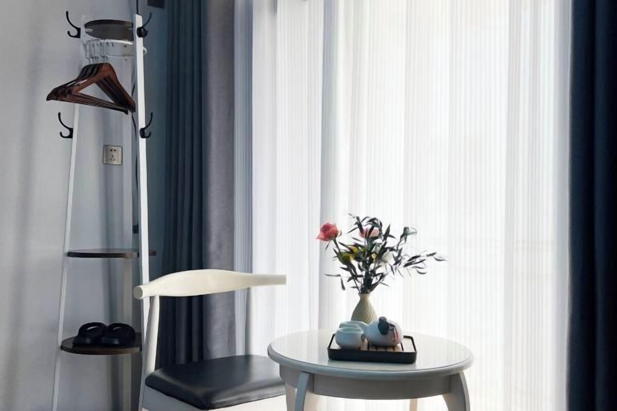 A modern room with a chair, a small table with a vase of flowers, and a shoe rack.