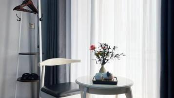 Quarto moderno com uma cadeira, uma mesinha com um vaso de flores e um sapateiro.