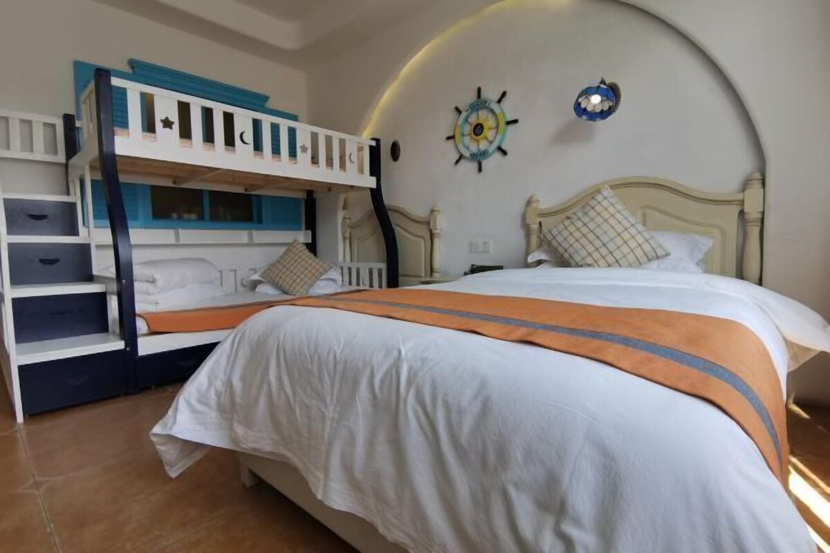 A bedroom with bunk beds, a large bed, and a curved wall with decorative elements.