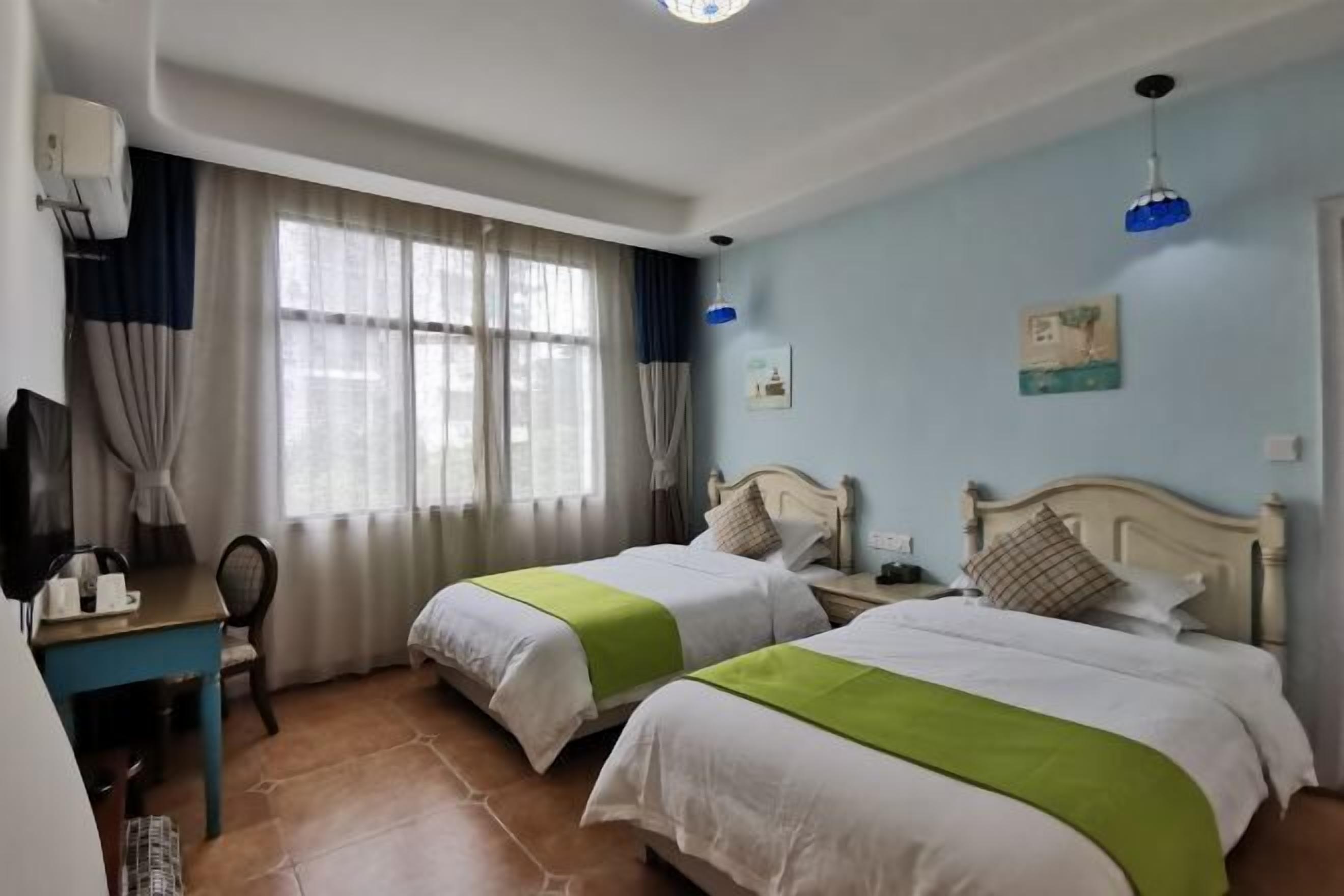 Habitación de hotel con dos camas, un escritorio, una silla y una televisión.