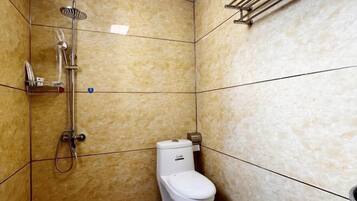 Une salle de bain avec une douche, des toilettes et un porte-serviettes.