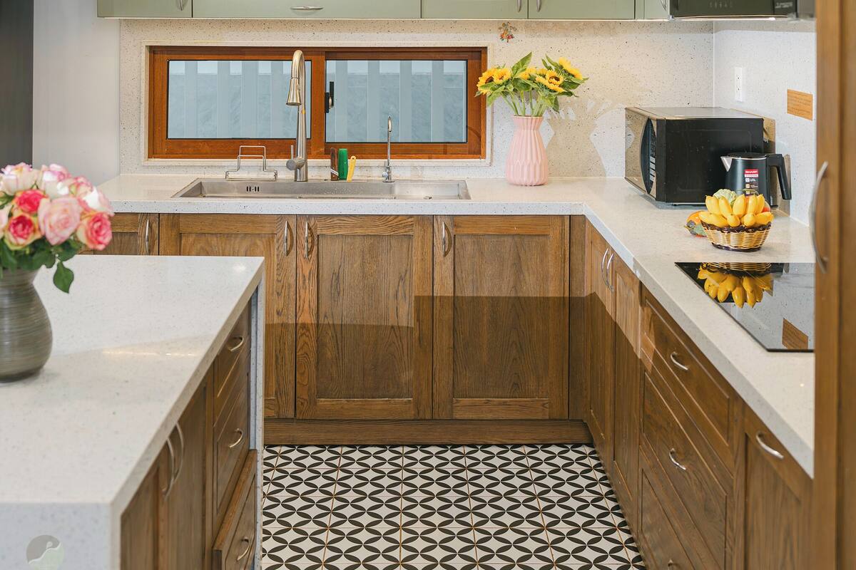 A kitchen with green cabinets, a stainless steel sink, a microwave, and a patterned floor.