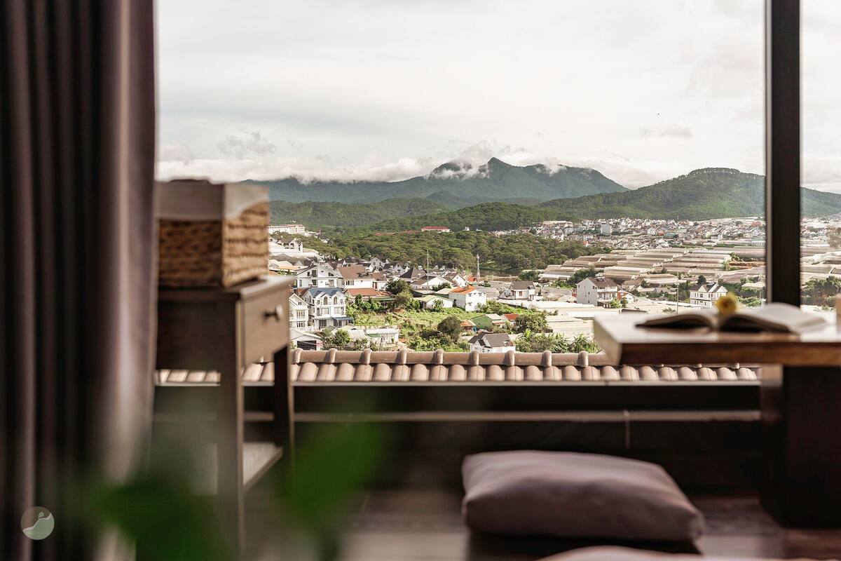 A room with a view of a town and mountains.
