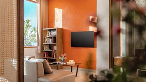 A modern living room with a sofa, coffee table, bookshelf, and a flat-screen TV mounted on the wall. - Mien Suong Khoi - Home & Cafe (Xuan Truong - Da Lat)