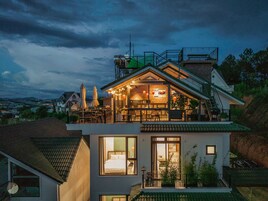 Uma casa de dois andares com varanda, janelas amplas e vista para a paisagem ao redor.