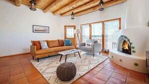 A living room with a wooden ceiling, a fireplace, a sofa, a chair, and a rug. - Casa Escondido- Quiet | Decks | 3BR | El Dorado (Santa Fe)