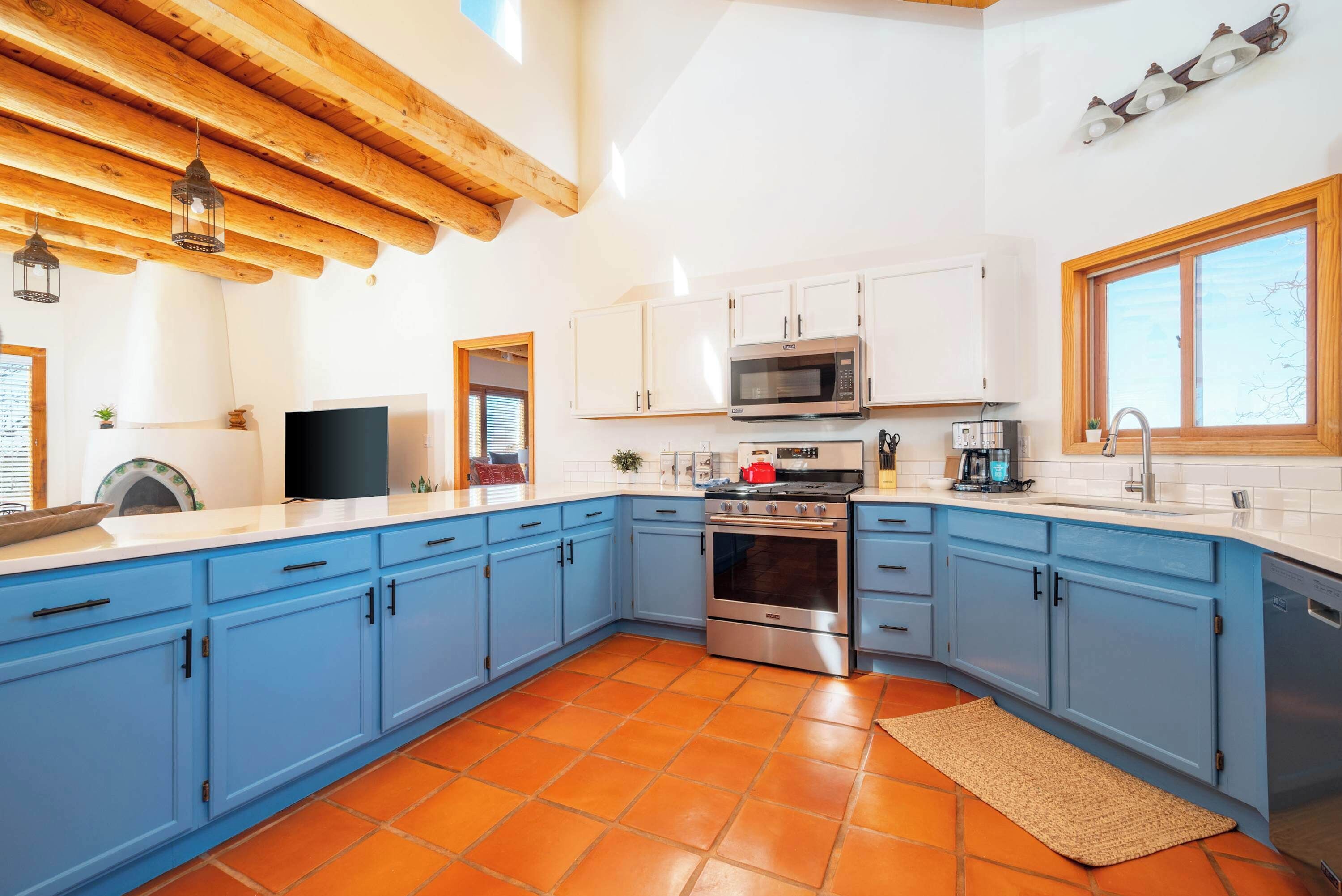 Una cocina con armarios azules, un microondas, un horno y un lavabo.