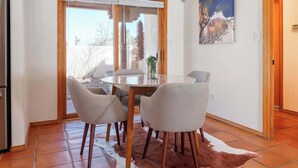 A dining area with a round table, four chairs, a cowhide rug, and a painting on the wall. - Casa Escondido- Quiet | Decks | 3BR | El Dorado (Santa Fe)