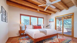 A bedroom with a wooden ceiling, a bed with a patterned rug, a window, and a sliding glass door leading to an outdoor area. - Casa Escondido- Quiet | Decks | 3BR | El Dorado (Santa Fe)