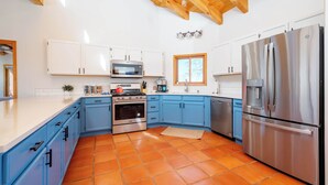 A kitchen with blue cabinets, a stainless steel refrigerator, a microwave, and a stove. - Casa Escondido- Quiet | Decks | 3BR | El Dorado (Santa Fe)