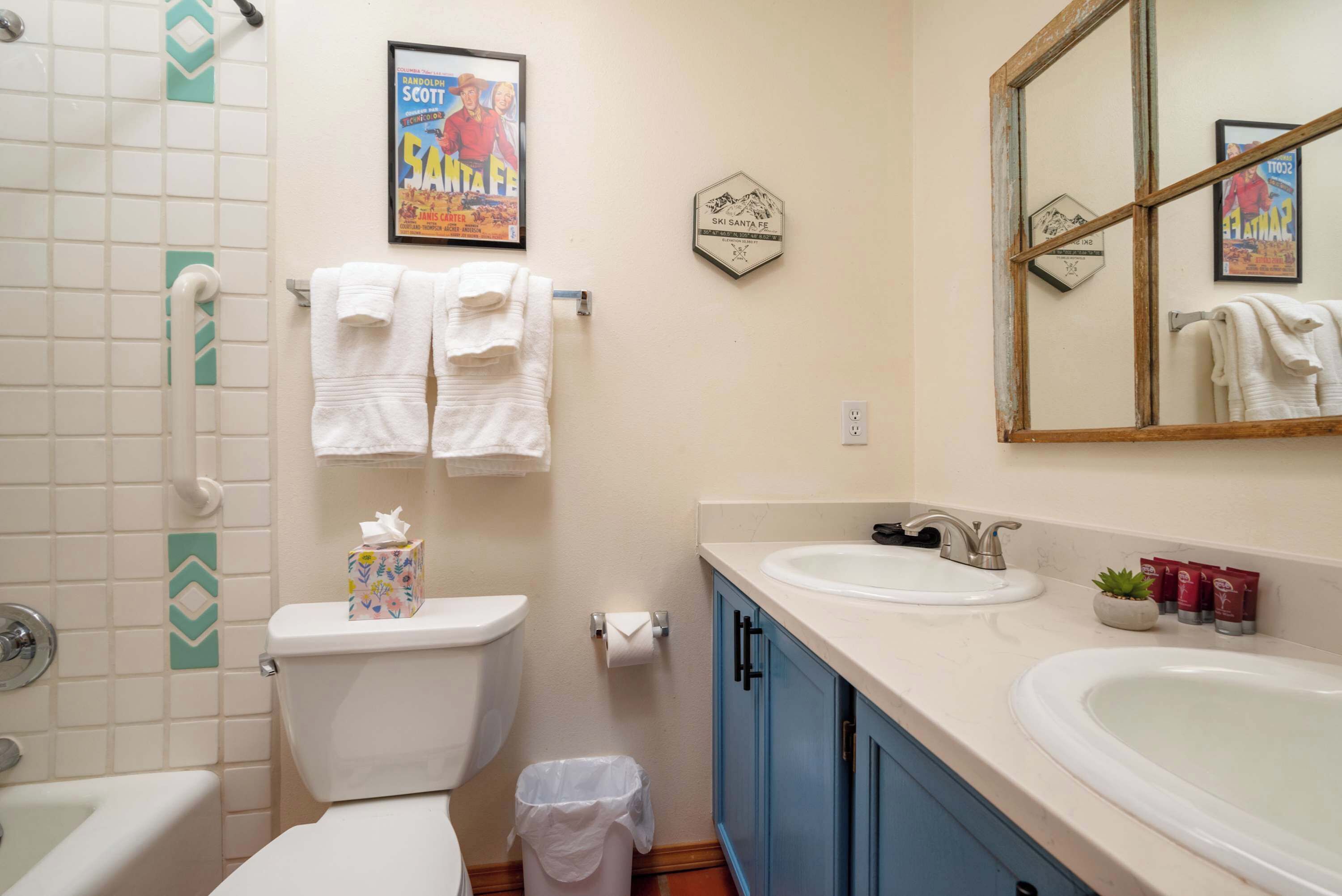 A bathroom with a toilet, two sinks, a mirror, and towels.