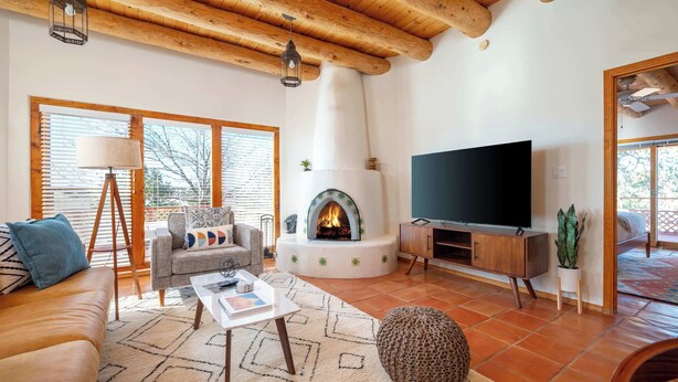 A living room with a fireplace, sofa, TV, and wooden ceiling beams. - Casa Escondido- Quiet | Decks | 3BR | El Dorado (Santa Fe)