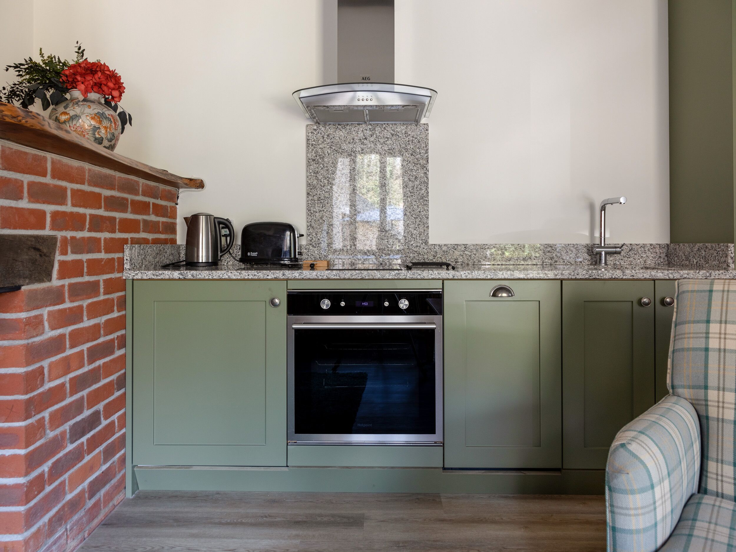 A kitchen with a built-in oven, a kettle, and a toaster on the countertop.