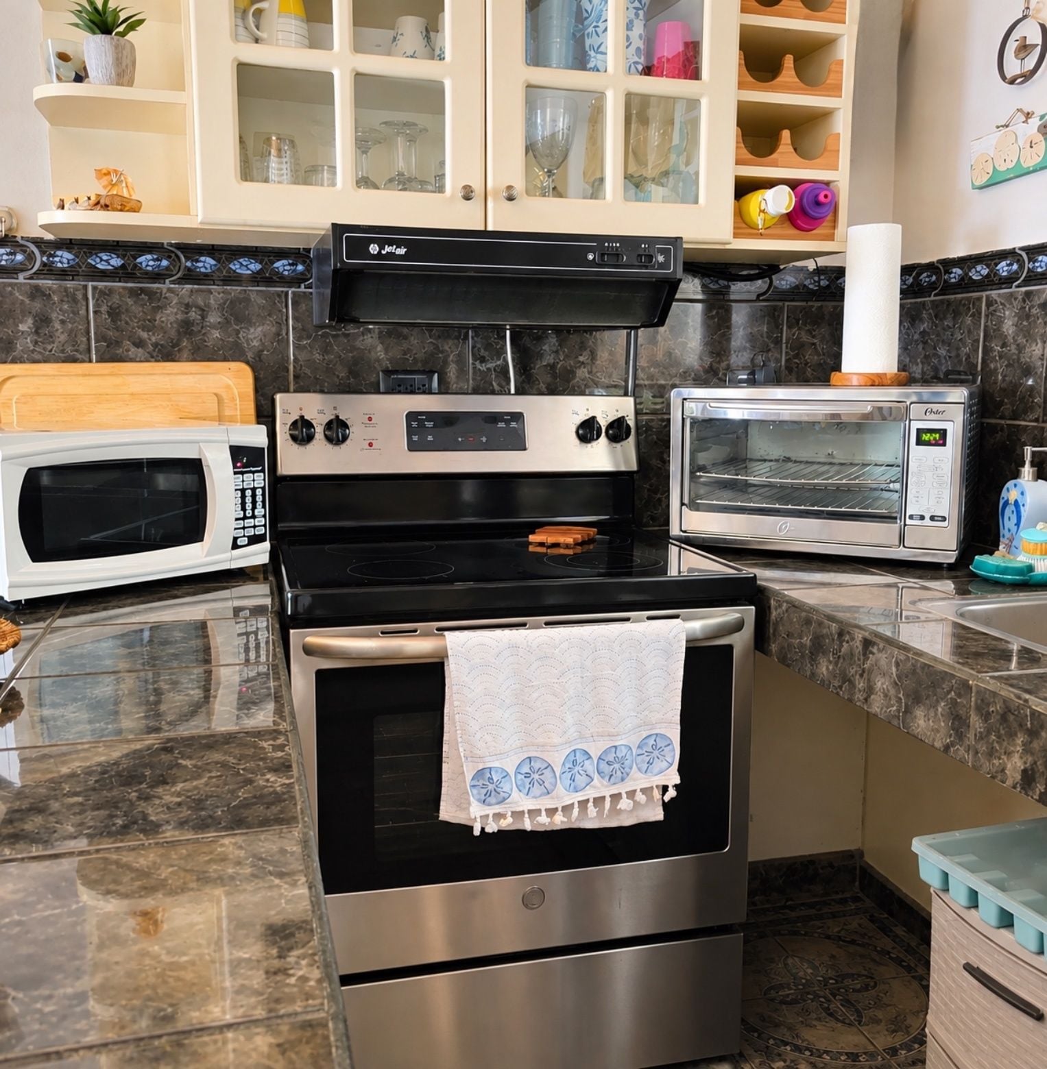 A kitchen with a stove, microwave, and toaster oven.