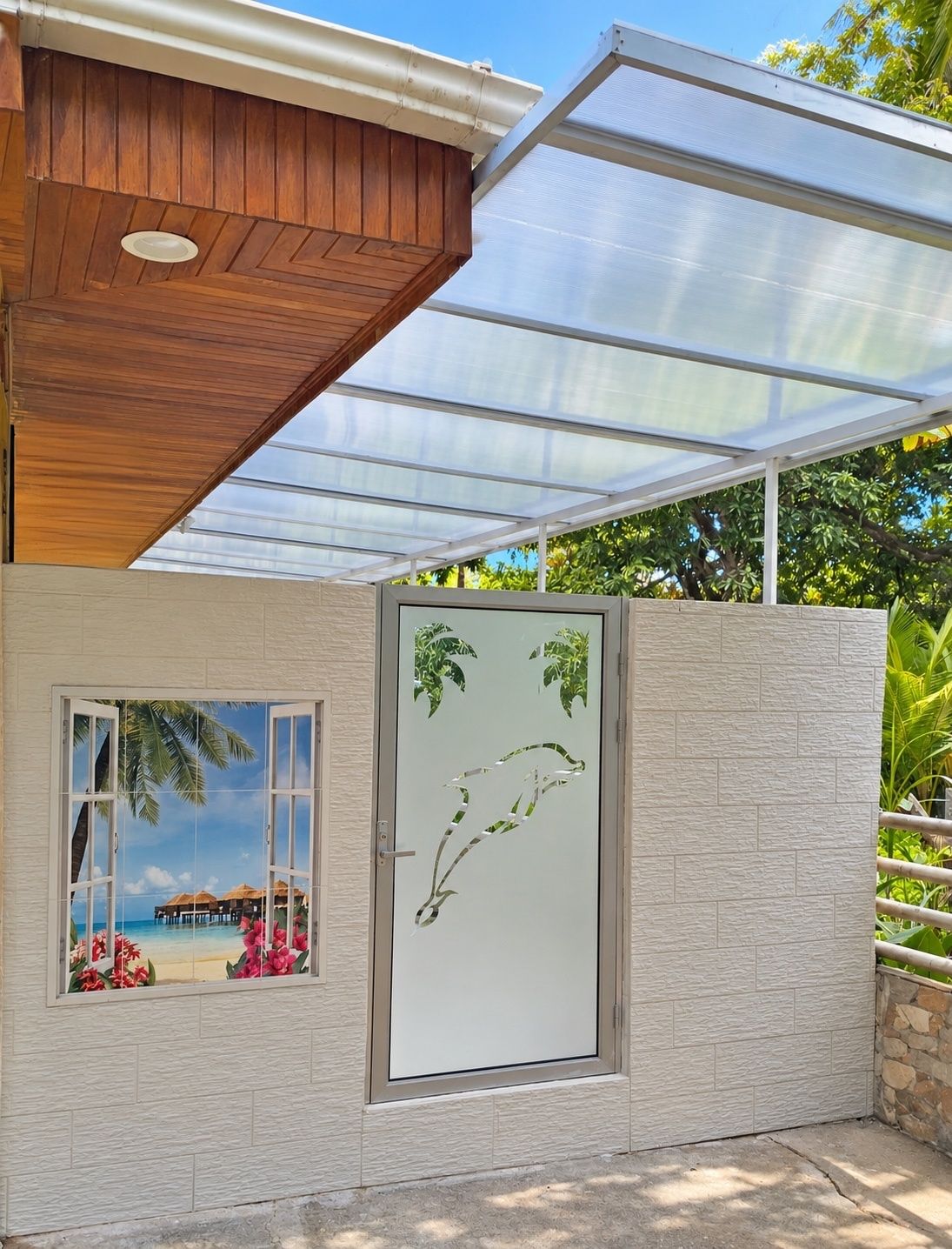 A modern building with a wooden ceiling, a glass door with a tropical scene, and a view of a beach.