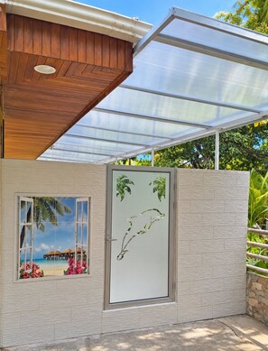 A modern building with a wooden ceiling, a glass door with a tropical scene, and a view of a beach.