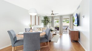 Ein moderner Essbereich mit einem runden Tisch, grau gepolsterten Stühlen und einem Deckenventilator.