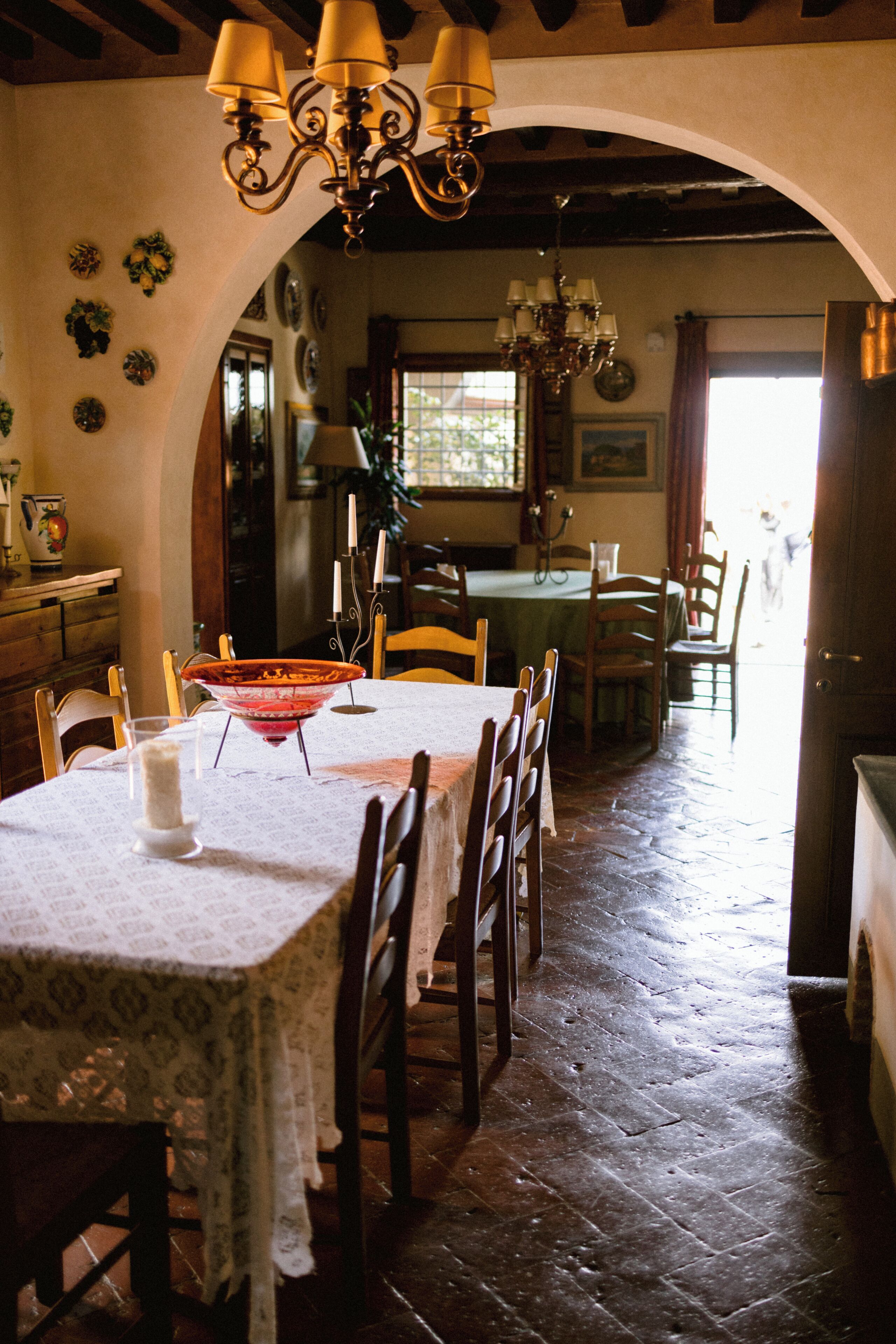 Zona pranzo con tavolo apparecchiato per quattro, circondato da sedie in legno. Un arco conduce a un'altra stanza.