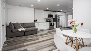 Una cocina moderna con armarios blancos, un refrigerador de acero inoxidable y un microondas.