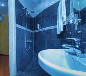 A bathroom with a white sink, a shower with a handheld showerhead, and a towel rack. - Irmeni (Tbilisi)