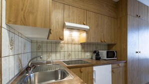 Une cuisine avec des meubles en bois, un évier en acier inoxydable, un four à micro-ondes et un lave-vaisselle.