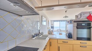 A modern kitchen with a granite countertop, stainless steel appliances, and a view to the outside. - Duplex Etoile de mer- T4 Vue mer (Courseulles-sur-Mer)