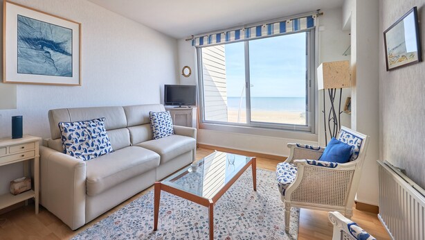 A living room with a sofa, armchair, coffee table, and a TV. - Duplex Etoile de mer- T4 Vue mer (Courseulles-sur-Mer)
