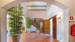 A spacious hallway with a tiled floor, a staircase, and a large potted plant. - Villa Breena - Quinta do Mar (Quinta do Lago)