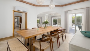 A spacious dining area with a wooden table, wicker chairs, and a vase of flowers. - Villa Flamingo - Quinta do Mar  (Vale do Lobo)