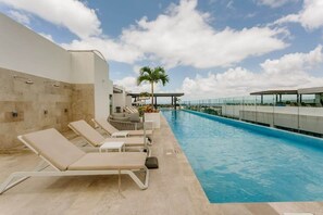 A poolside area with lounge chairs and a palm tree.
