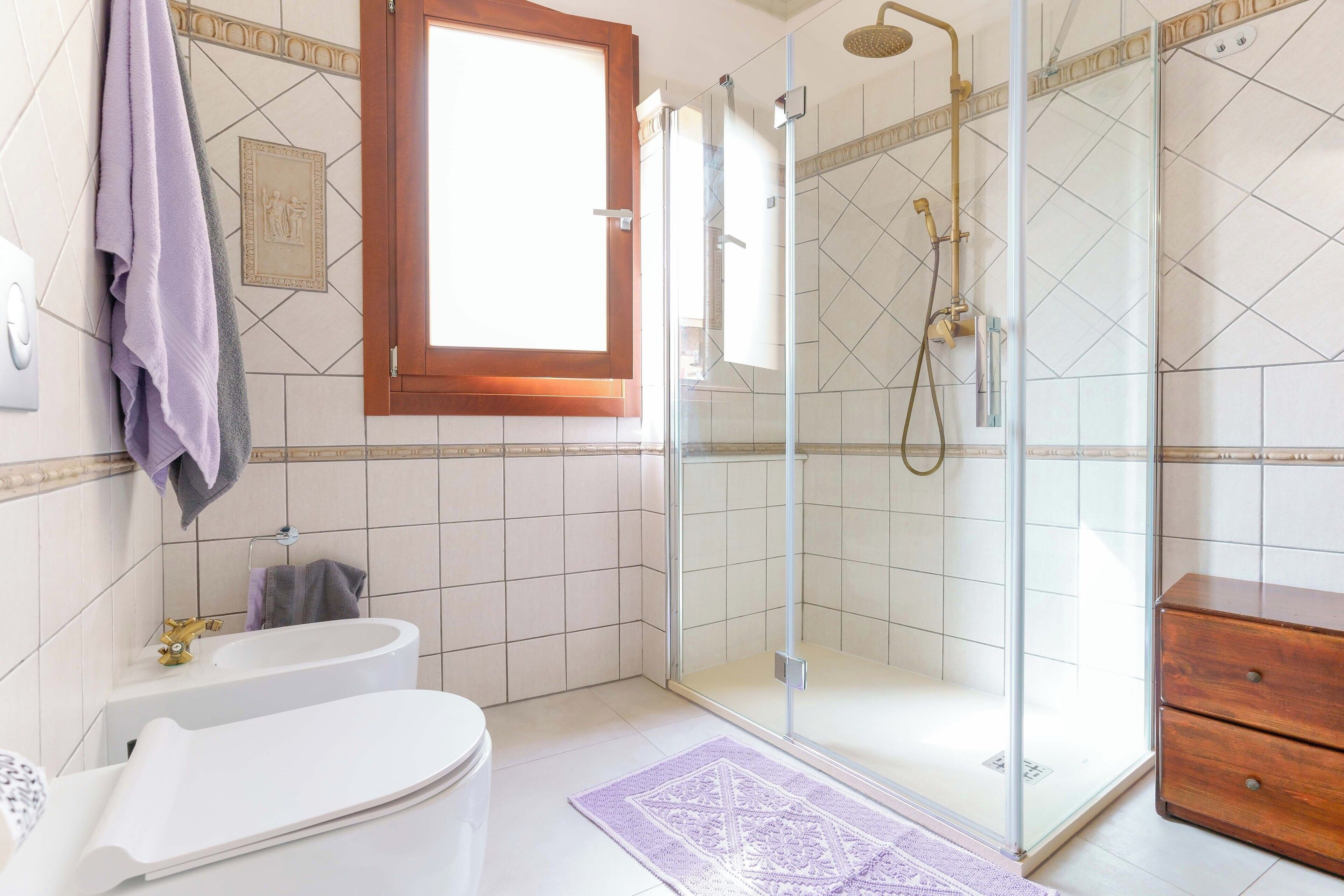 Une salle de bain avec une douche à parois de verre, une baignoire blanche et un meuble en bois.