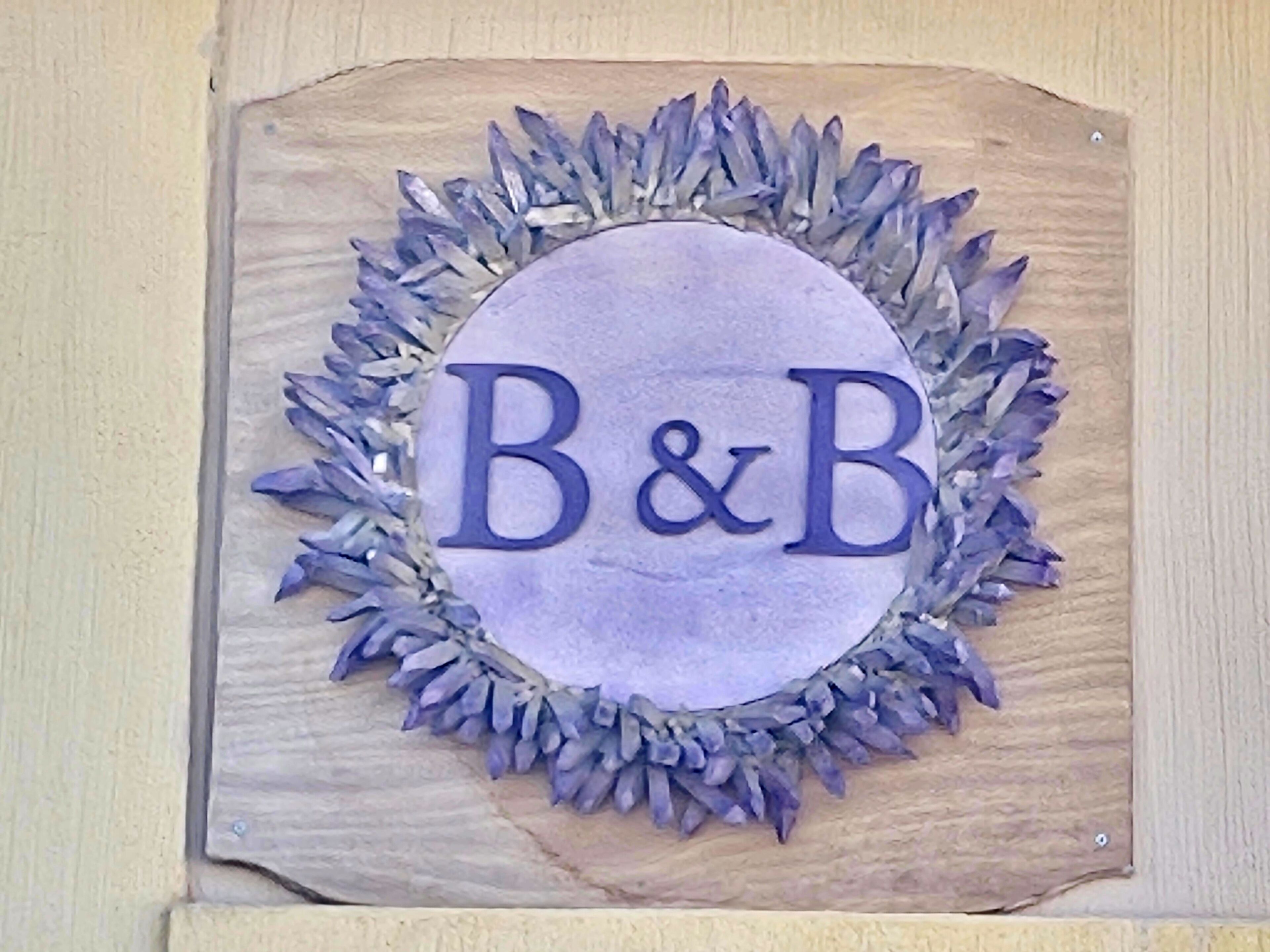 Un letrero de madera con un círculo central y las letras 'B&B' en el centro.