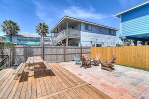 Un jardin avec une terrasse en bois, du mobilier d’extérieur et une zone délimitée par une clôture.
