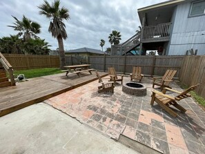 Un jardin avec un foyer, des chaises en bois et une terrasse en bois.