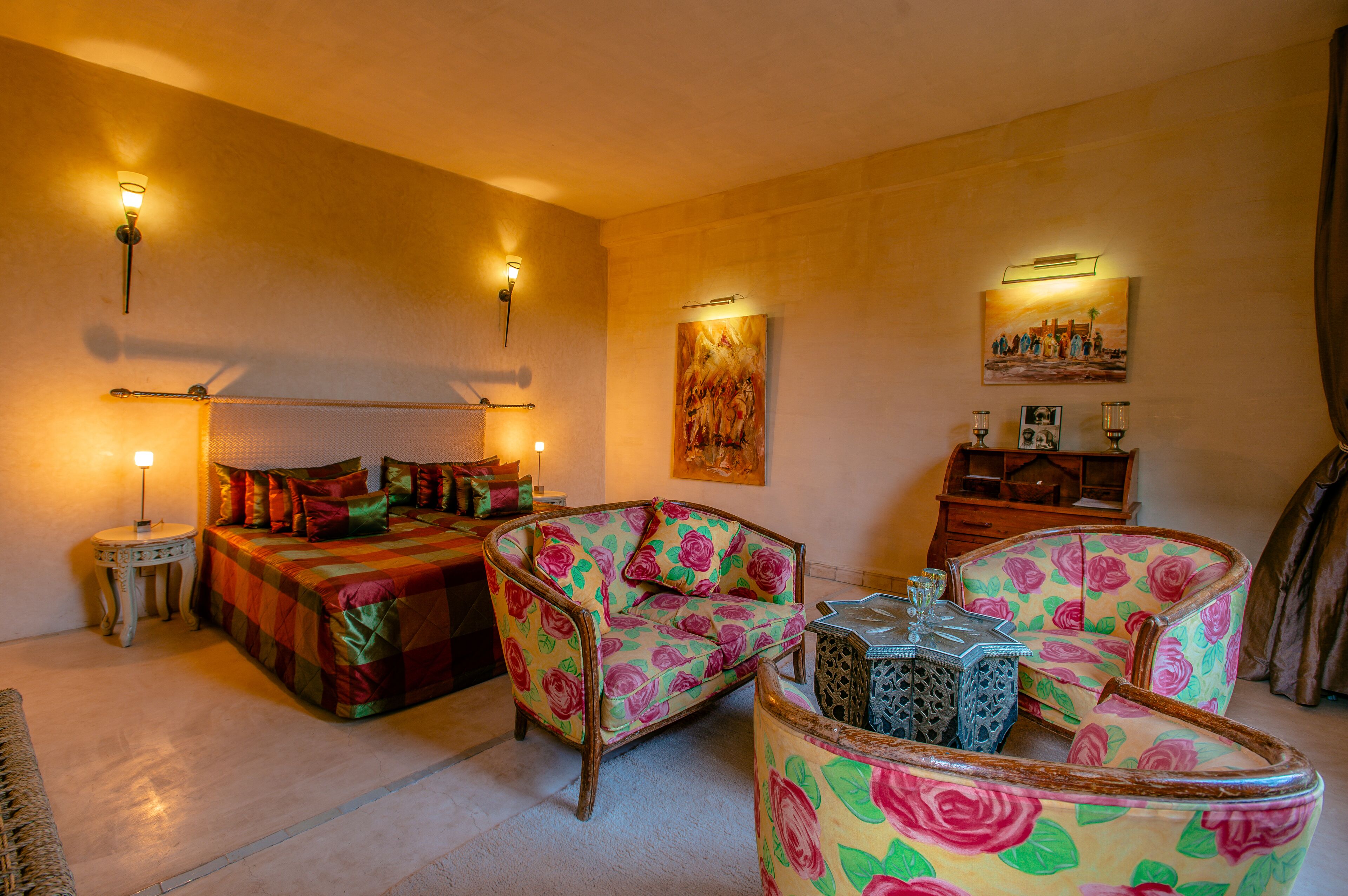 Een kamer met een bed, twee fauteuils, een tafeltje en een kast.