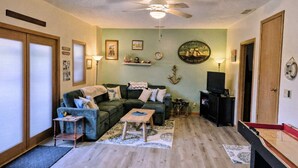 Un salon avec un canapé vert, une table basse, un téléviseur et un ventilateur de plafond.