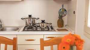 Una cocina con estufa a gas, ollas de acero inoxidable, una piña y un salpicadero decorativo de azulejos.